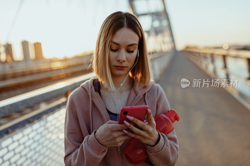 一名年轻女子戴着耳机在户外慢跑