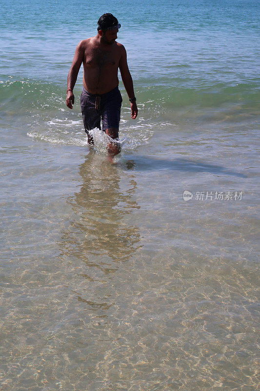 一名印度男子在海滩度假，走出大海，从印度洋回到海滩，海浪翻滚到沙滩上，印度果阿的帕洛伦海滩