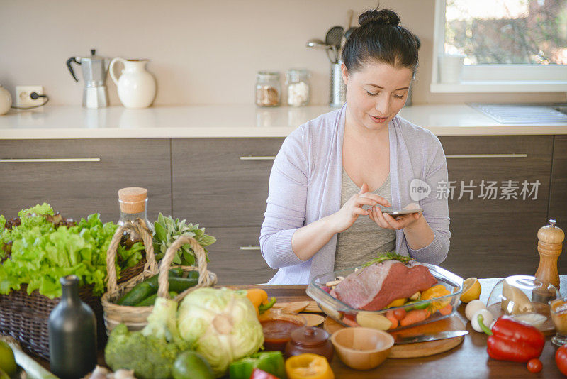 女人在厨房做饭(牛肉和智能手机)