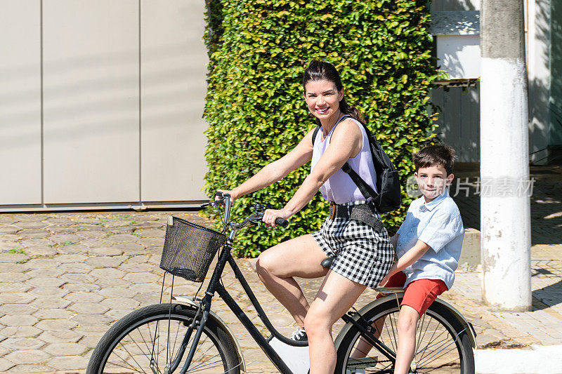 一对巴西母亲和儿子骑着自行车看着镜头。