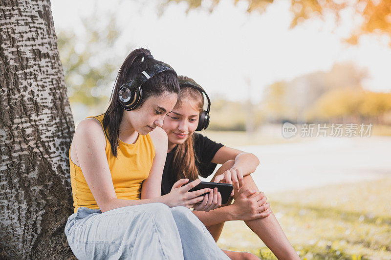 快乐的青少年用蓝牙耳机和智能手机听音乐。