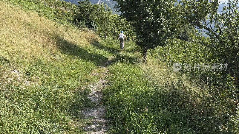 女山地自行车手沿着小路穿过草地