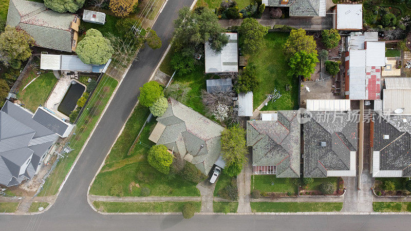 在墨尔本远郊一条安静的街道上，用无人机从上到下俯瞰着一个由20世纪中期的澳大利亚房屋和庭院组成的小社区