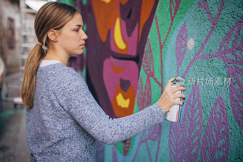 女艺术家在建筑墙上喷绘
