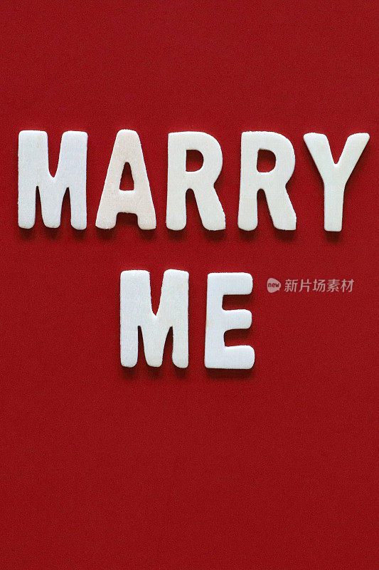 自制DIY简单的求婚卡设计的图像在红色背景上剪出白色字母，手工结婚我的贺卡信息