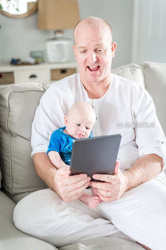 男子使用数码平板电脑与他的婴儿儿子进行FaceTime技术连接和团聚