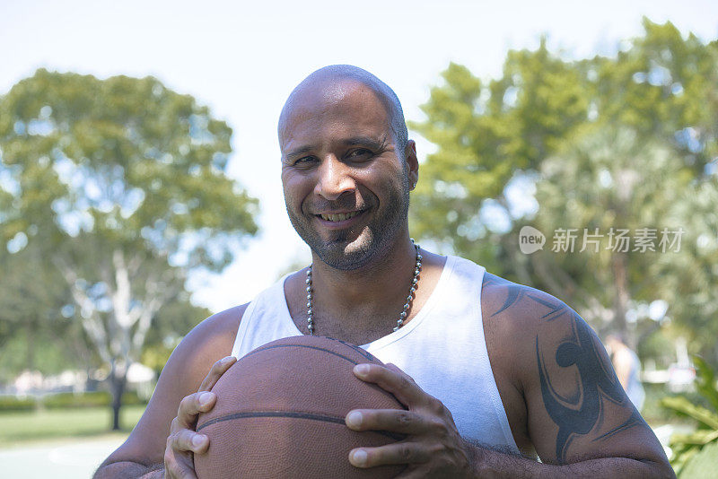 户外球场上快乐的篮球运动员手持球的肖像