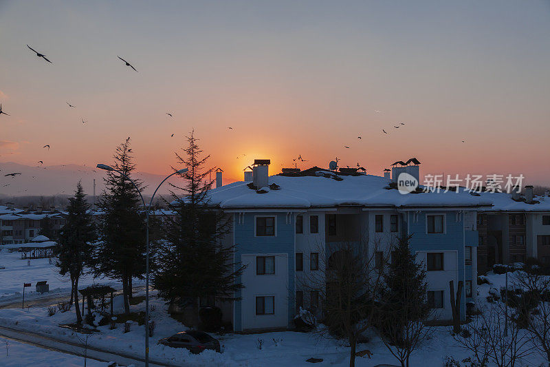 在一个下雪的冬日，夕阳和房子。