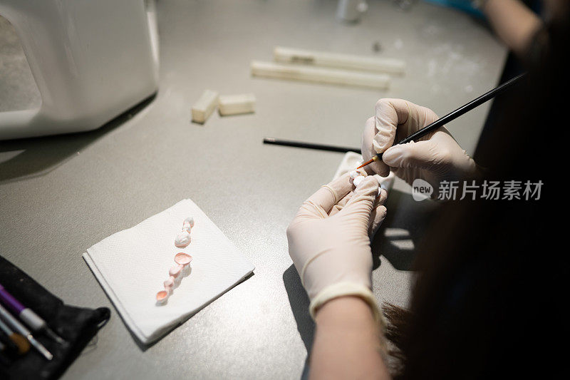 牙科实验室里，一位不知名的女技术员，正在制作假牙