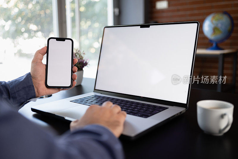 在肩膀上方看笔记本电脑和智能手机的白色空白屏幕
