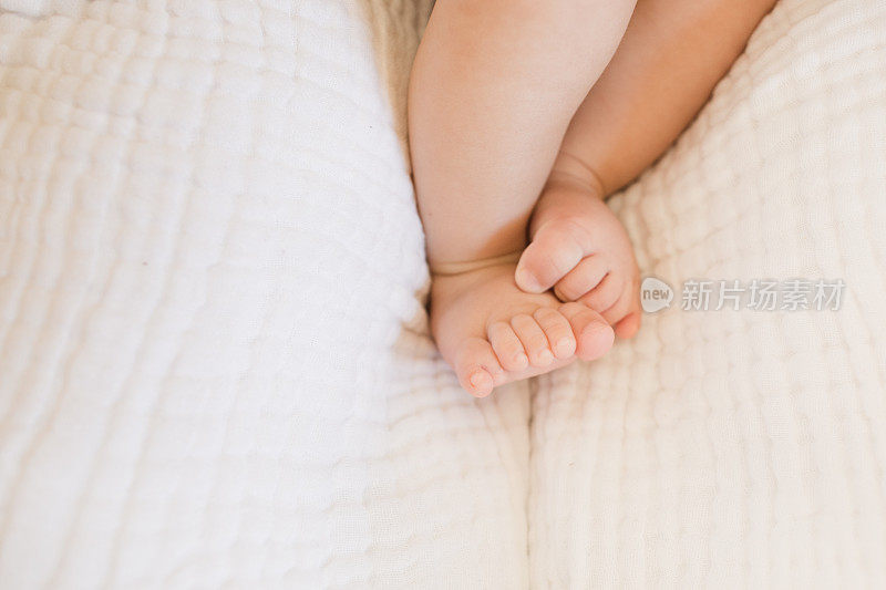一个27周大的男婴的脚与12个脚趾蜷缩在一个舒适的棉毯在海草摩西篮子