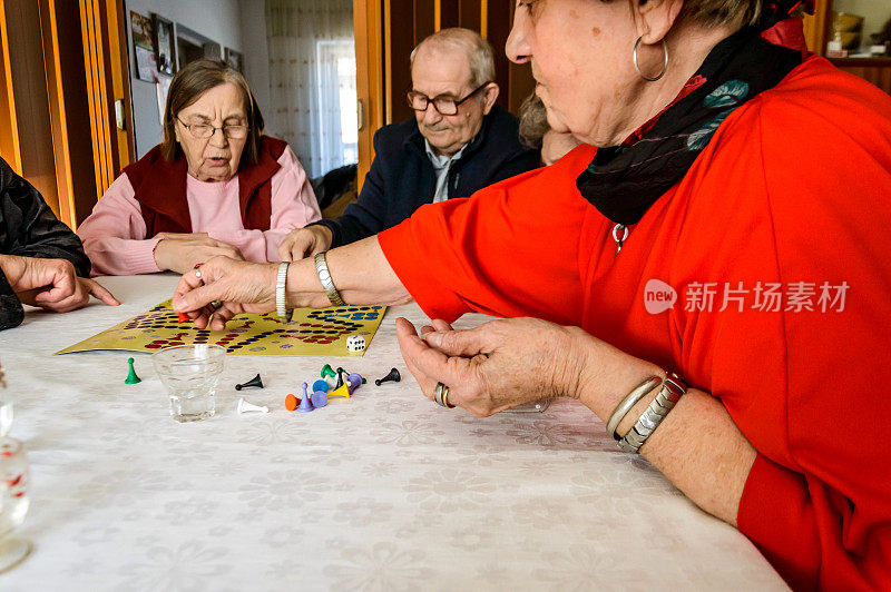 在一次社交聚会上，一群年长的人正在玩ludo游戏，玩得很开心。