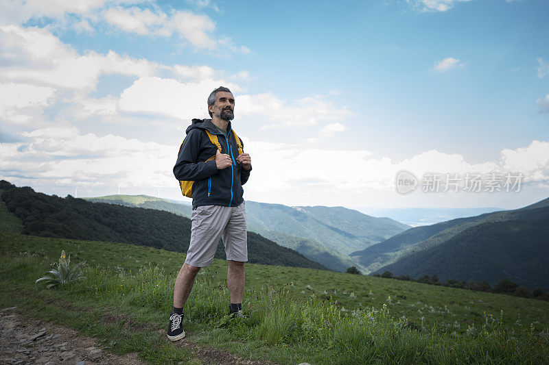 成熟的游客在一个阳光明媚的日子在树林里徒步旅行。