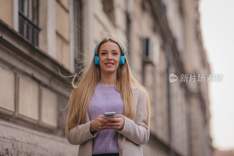 年轻自信的女人在街上听音乐的肖像