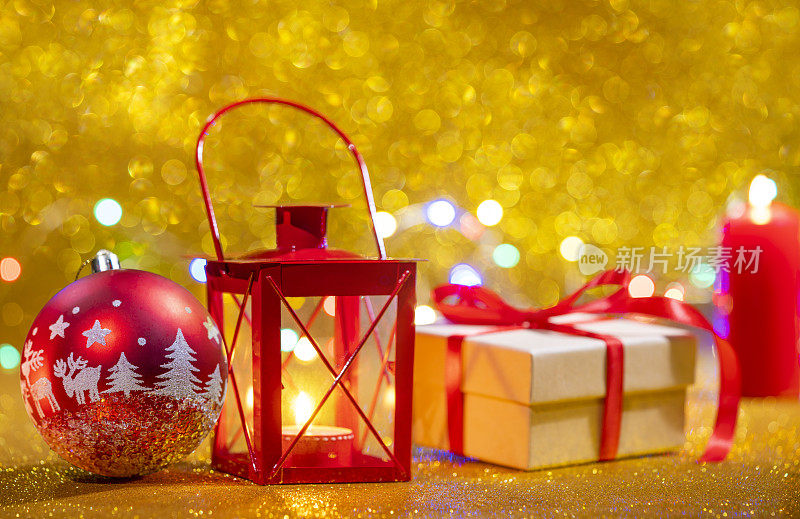 红色的蜡烛灯笼和礼品盒，金色的闪光圣诞背景，红色的小彩灯