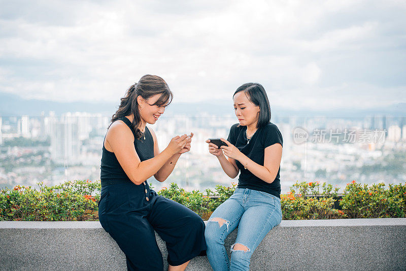 两位亚裔中国女性正在用手机玩手机游戏