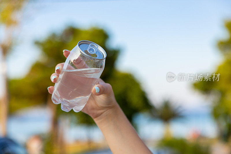 面目全非的女子拿着装着水的塑料罐，以大自然为背景