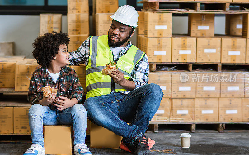 单身非洲工人父亲，抱着儿子，端着咖啡，汉堡，一起吃午饭，开心的微笑，休息，在工厂上班送货。家族，行业经营理念。