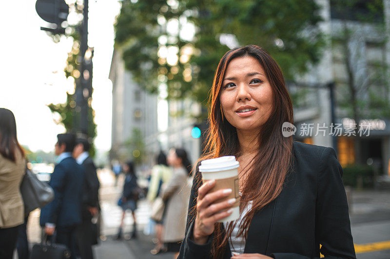 漂亮的日本女性在城市通勤时喝一杯咖啡