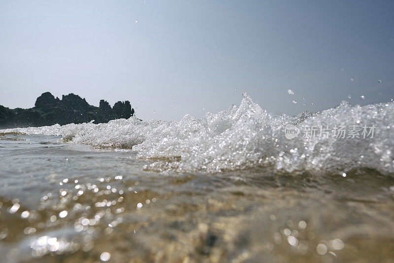 6月的一个晴朗的日子里，康沃尔郡的佩顿温德海滩上，海浪在镜头前翻滚。