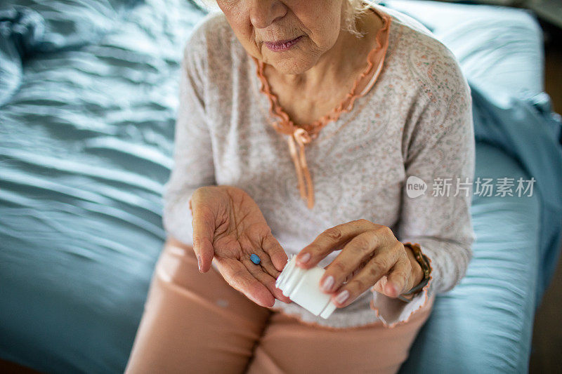 一个年长的女人在卧室里从药瓶里拿药