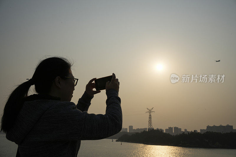 这位亚洲妇女正在用手机拍摄风景