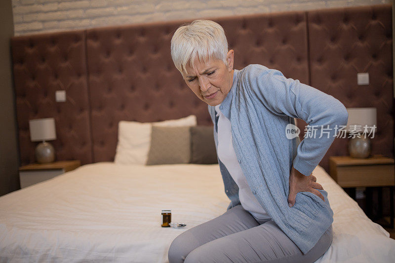 背部疼痛的老年妇女坐在沙发上