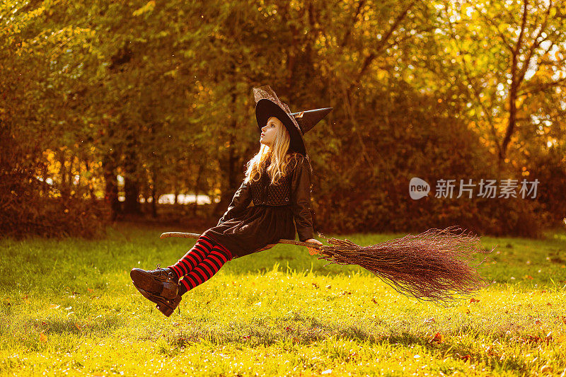 一个穿着女巫服装的女孩坐在漂浮的扫帚上