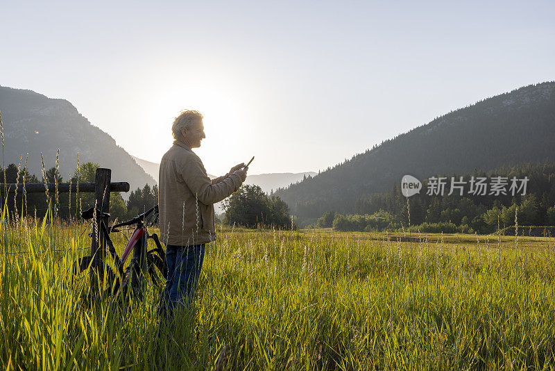 牧场主在木栅栏旁休息时使用数字平板电脑