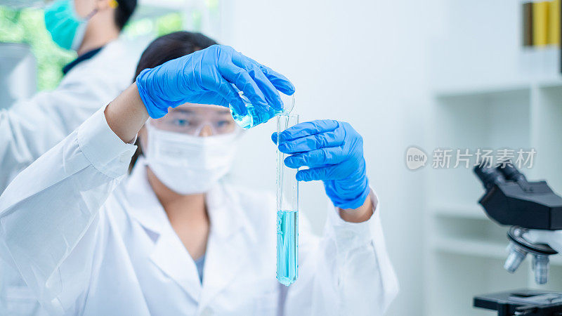 图为女科学家或研究人员正在向样品试管中注入蓝色物质或液体。科学概念，生物化学，化学实验室。物质研究分析实验。