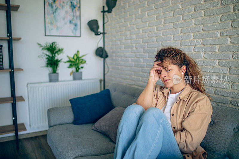 年轻女子在家里的沙发上头痛