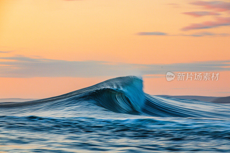 平滑弯曲的波浪在海洋与金色的天空黄昏与慢快门