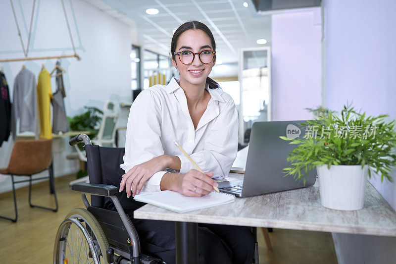 一个坐在轮椅上的漂亮女孩在共享办公中心用笔记本电脑工作的照片