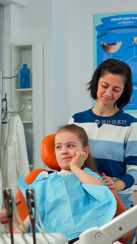 当牙医与母亲谈话时，孩子用手指指着患病的牙齿