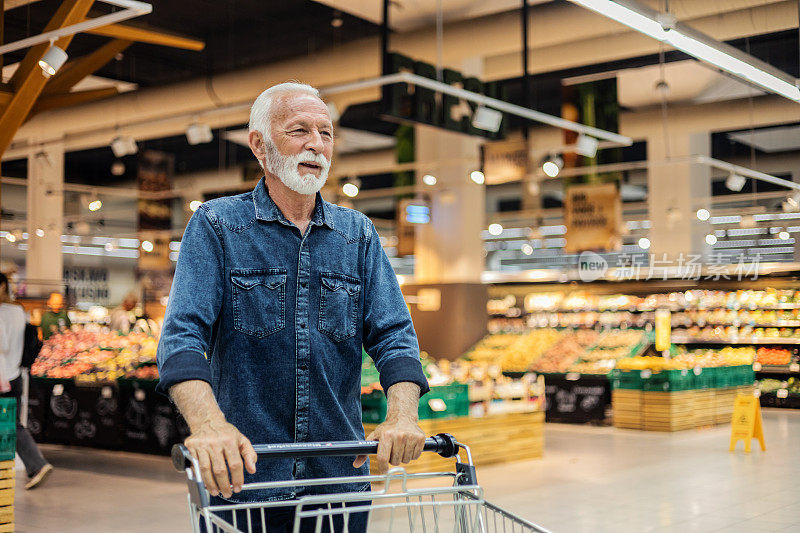 一个60多岁的英俊男人在每周的杂货店购物中穿过超市的过道，买了一些食物。