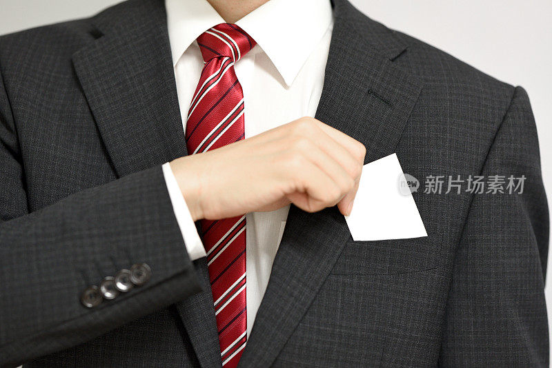 一个西装革履的亚洲男人从口袋里掏出一张名片