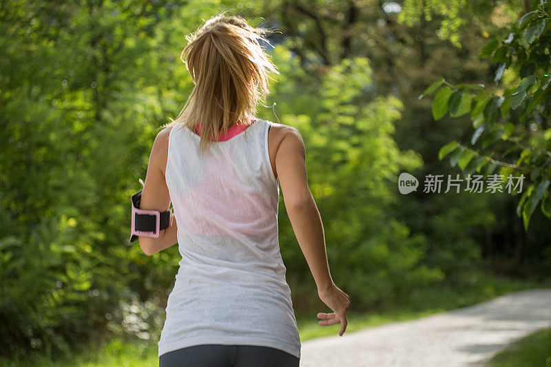 运动的年轻女子听音乐，同时在户外跑步