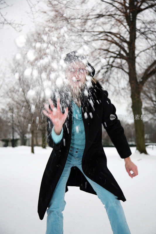 年轻女子在冰冷的雪地里扔雪球