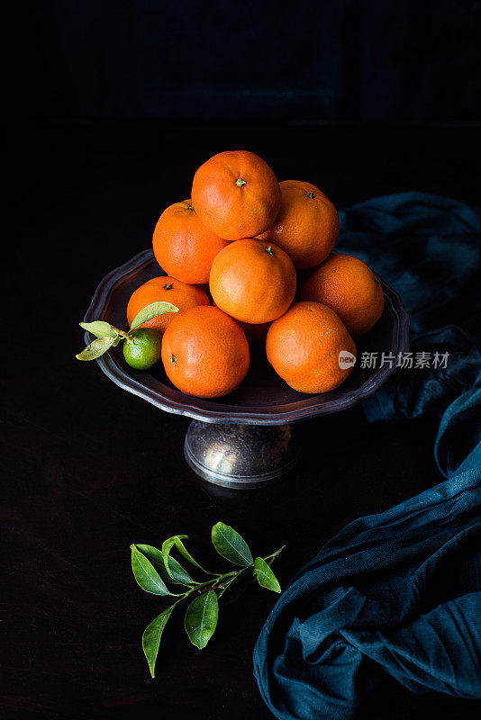 未成熟的绿色柑橘，叶子放在金属盘上