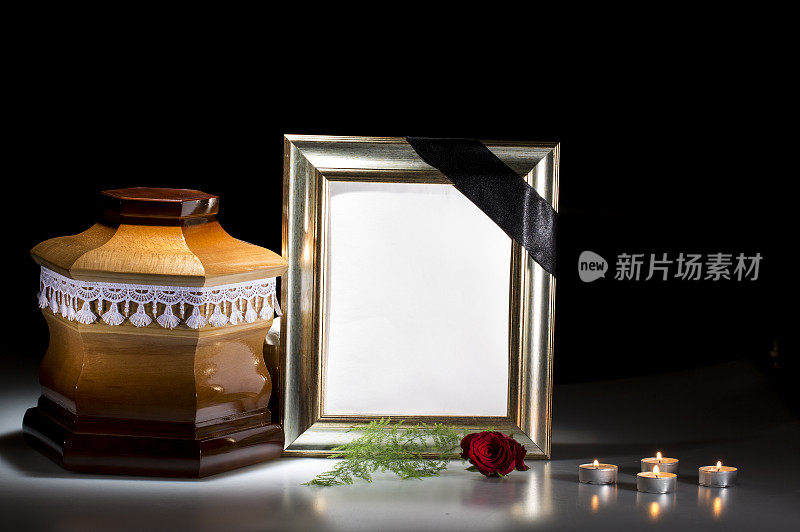 木制的墓园骨灰瓮，带有悼念框架和鲜花，蜡烛