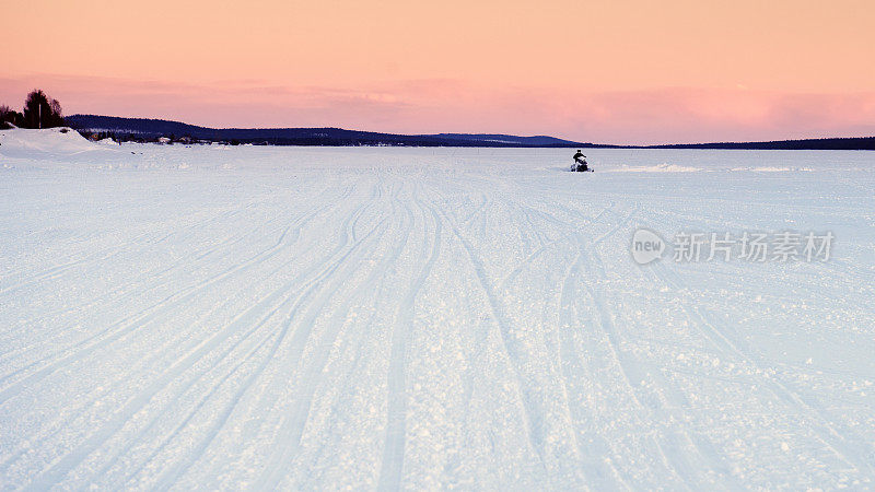 日落时分，雪地摩托在冰上行驶