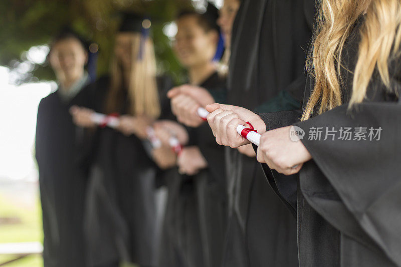 一群高中生拿着毕业证书，穿着长袍