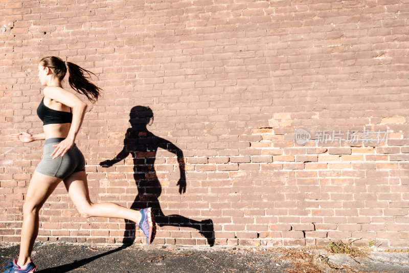 健身的女人在城市里对着墙跑