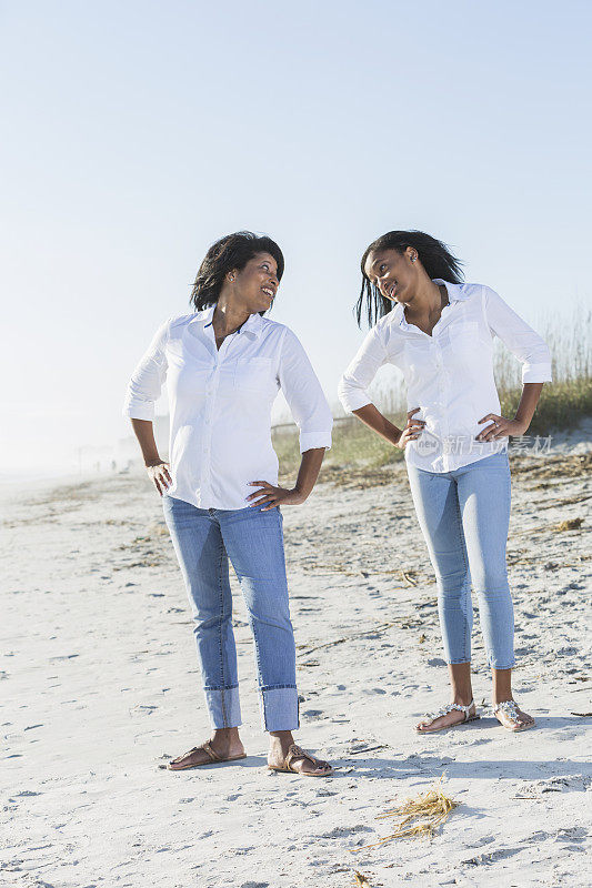 成熟的黑人女人，十几岁的女儿站在沙滩上