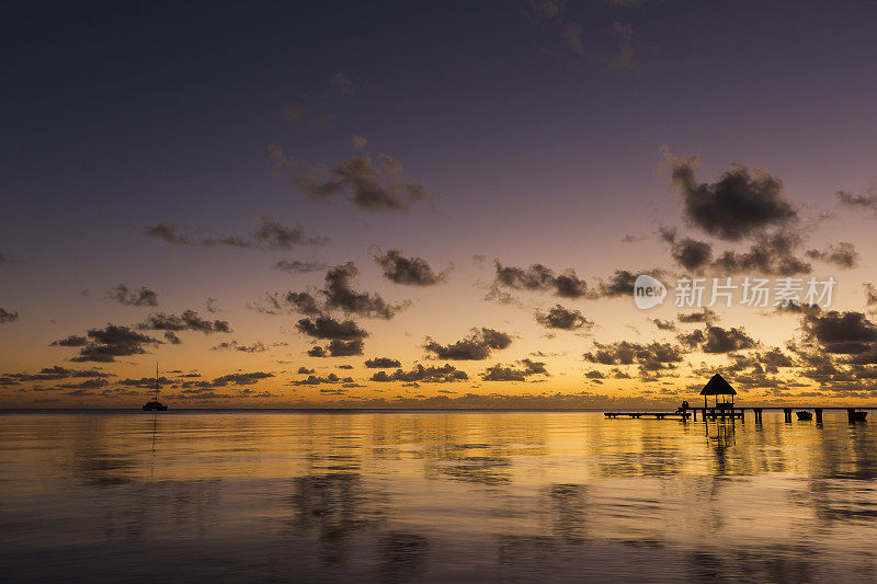 一对夫妇坐在远处的码头黄昏在Rangiroa