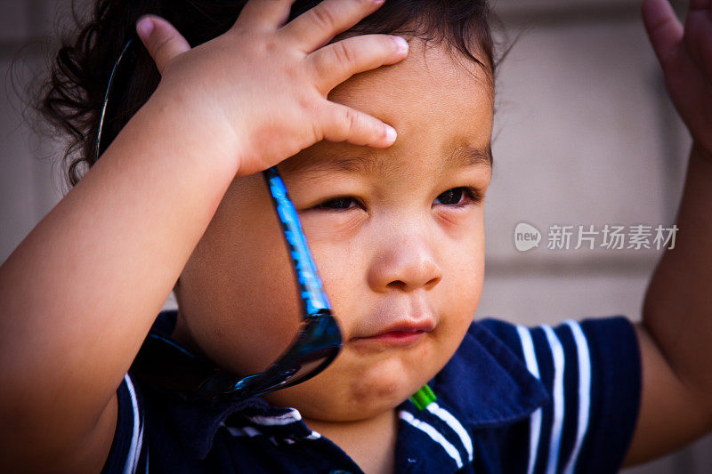 一个蹒跚学步的小孩抓着他的太阳镜