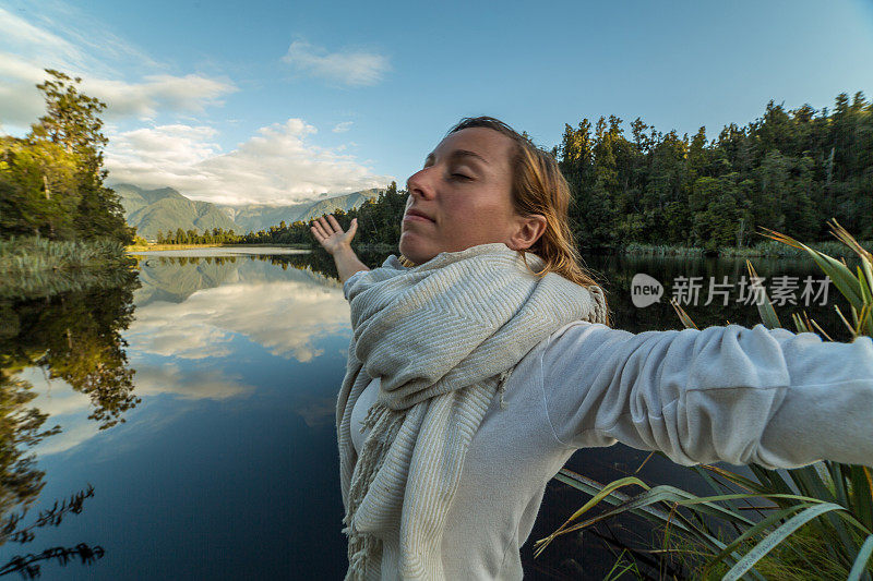 年轻女子在湖边张开双臂