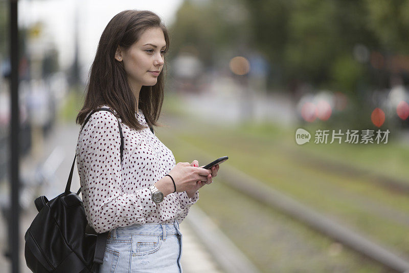 拿着电话等电车的女人