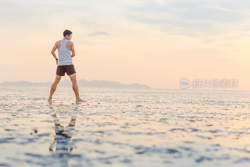 年轻的亚洲男子训练空手道和踢拳击在海滩