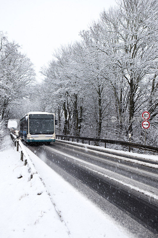 公交车在冬天的路上，下着大雪